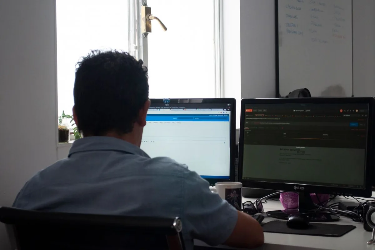 Profesional trabajando con información en dos monitores — imagen ilustrativa